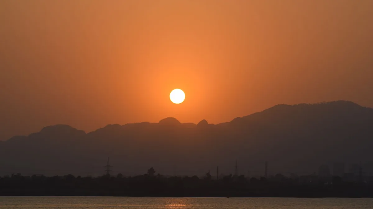 A breathtaking sunset view over mountains with a calm river in the foreground.